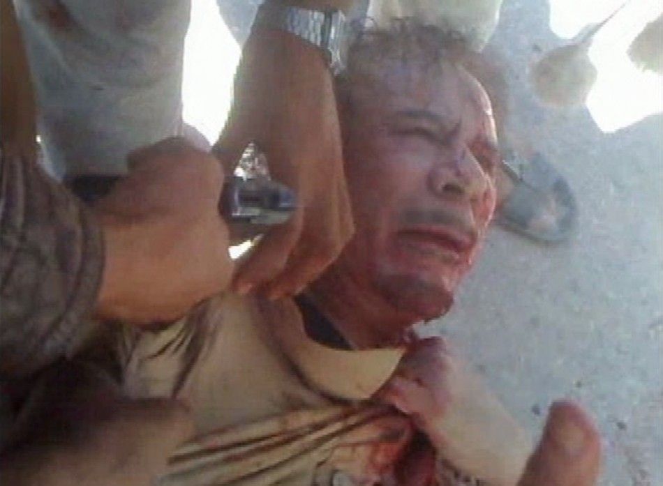An NTC fighter points a gun at Libya039s former leader Muammar Gaddafi in Sirte in this still image taken from video