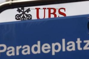The logo of Swiss bank UBS on the roof of the company's headquarters is seen behind a road sign at the Paradeplatz square in Zurich