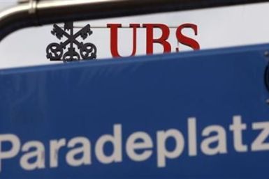 The logo of Swiss bank UBS on the roof of the company's headquarters is seen behind a road sign at the Paradeplatz square in Zurich