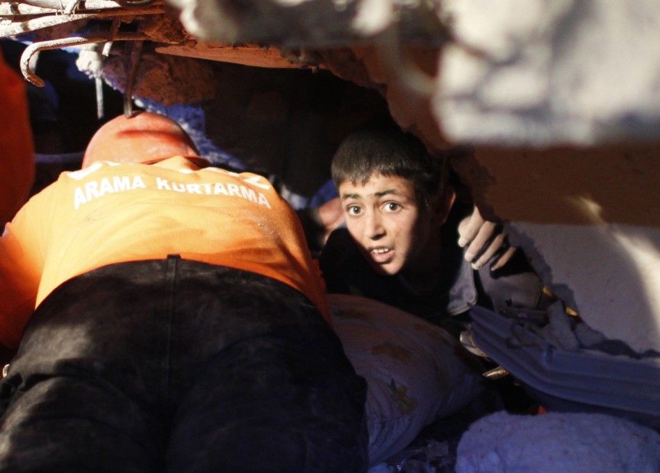 Yunus, a 13-year-old earthquake survivor, waits to be rescued from under a collapsed building by rescue workers in Ercis, near the eastern Turkish city of Van, early October 24, 2011.
