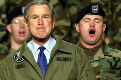 U.S. President George W. Bush listens as U.S. Army soldiers sing &quot;The Army Song&quot; during a stop at Fort Hood, Texas, January 3, 2003. Bush addressed the soldiers and their families about the possiblity of military action against Iraq.