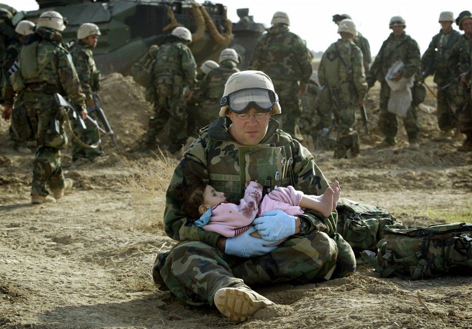 U.S. Navy Hospital Corpsman HM1 Richard Barnett, assigned to the 1st Marine Division, holds an Iraqi child in central Iraq in this March 29, 2003 file photo. Confused front line crossfire ripped apart an Iraqi family after local soldiers appeared to force