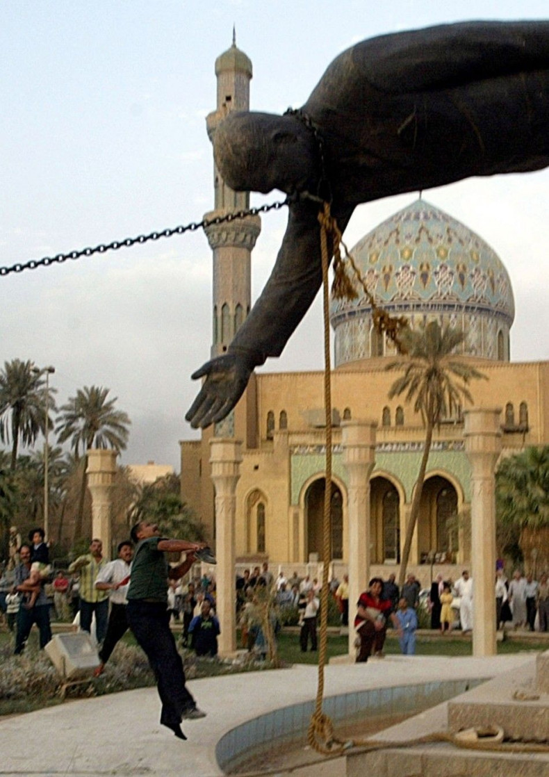 An Iraqi man throws stones at a statue of Iraq's President Saddam Hussein as it falls in central Baghdad April 9, 2003. U.S. troops pulled down a 20-foot (six metre) high statue of President Saddam Hussein in central Baghdad on Wednesday and Iraqis d