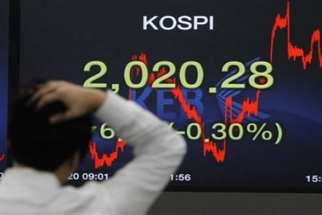 A foreign currency dealer walks past a screen displaying the Korea Composite Stock Price Index (KOSPI) at a bank in Seoul