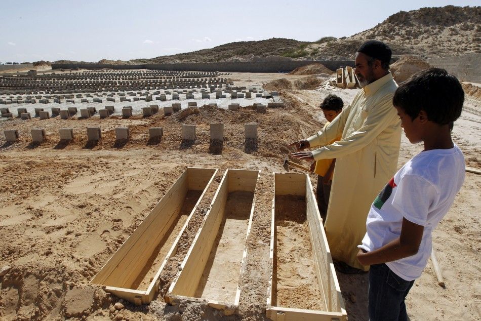 A man looks at empty coffins in a cemetery where soldiers loyal to former Libyan leader Muammar Gaddafi are being buried in Misrata October 25, 2011.