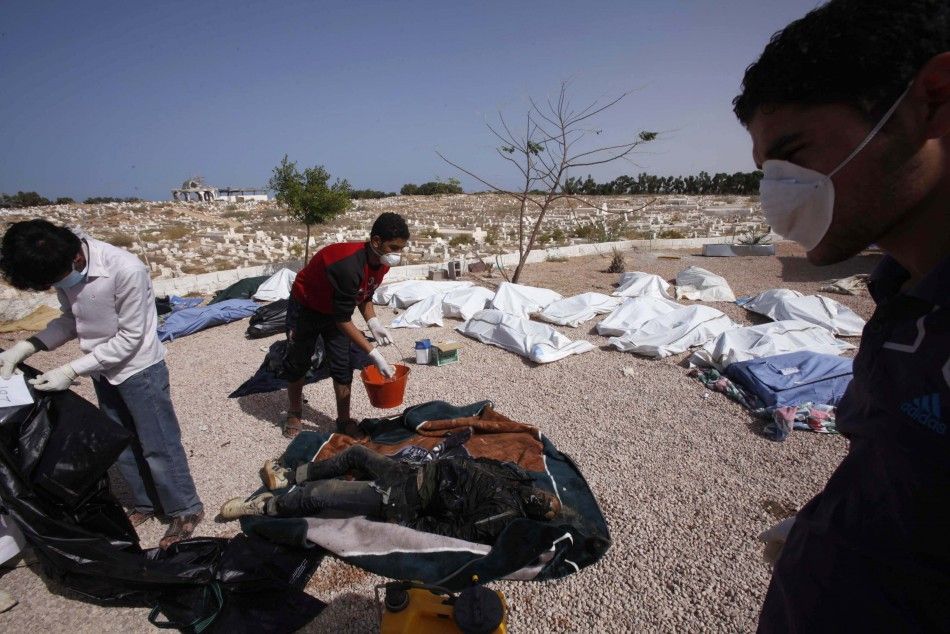 Men inspect about 45 bodies found in Bani Hawal cemetery in Sirte October 25, 2011.