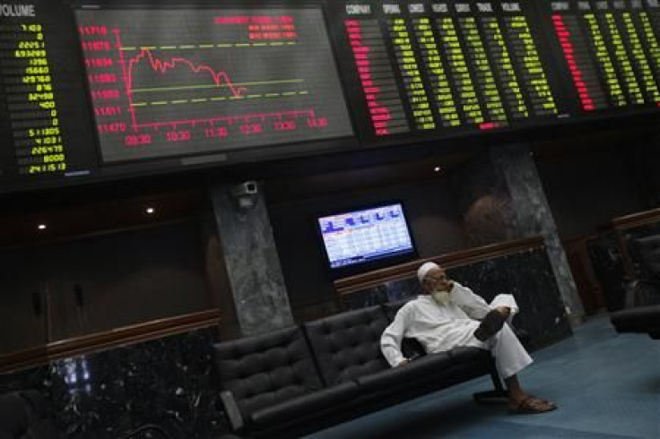 A stockbroker sits under an electronic board showing stock information at the Karachi Stock Exchange