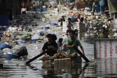 People push their belongings through floodwaters during an evacuation from a flooded market in Bangkok