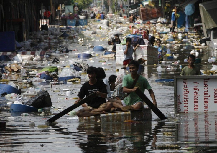 People push their belongings through floodwaters during an evacuation from a flooded market in Bangkok