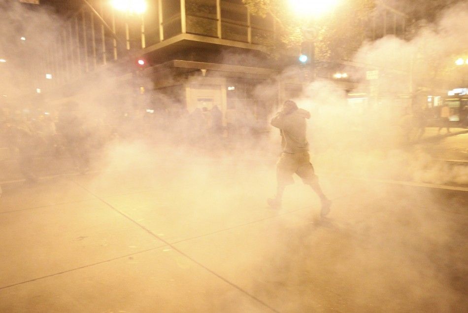 A masked Occupy Wall St. demonstrator walks away as authorities deploy tear gas during an demonstration in response to an early morning police raid which displaced Occupy Oaklands tent city in Oakland