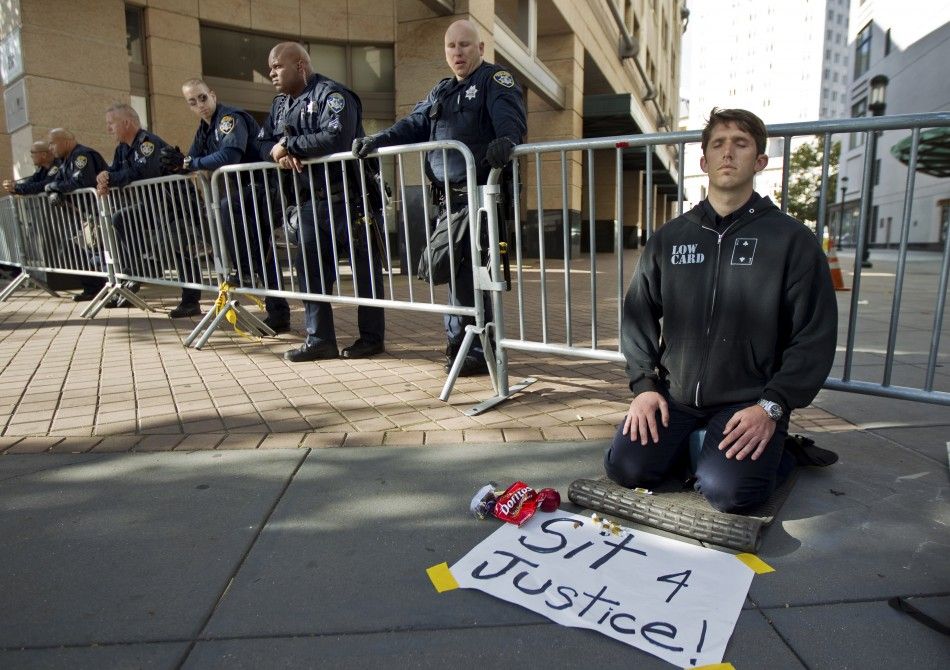 An anti-Wall Street protester kneels next to a police line in Oakland