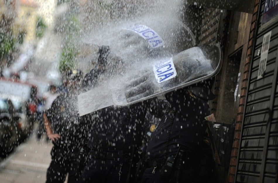 Police take cover from water dumped on them by Stop Desahucios activists during a June 27 eviciton in Oviedo, Spain.
