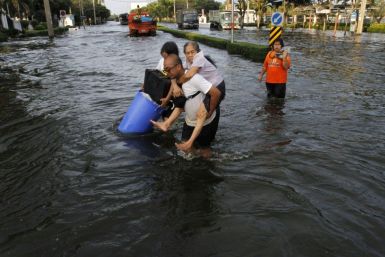 A man carries his mother during an evacuation as floods advance into Bangkok