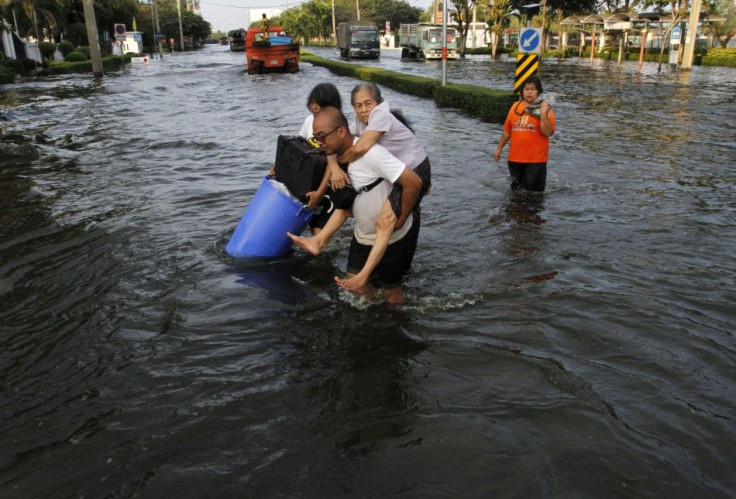 A man carries his mother during an evacuation as floods advance into Bangkok