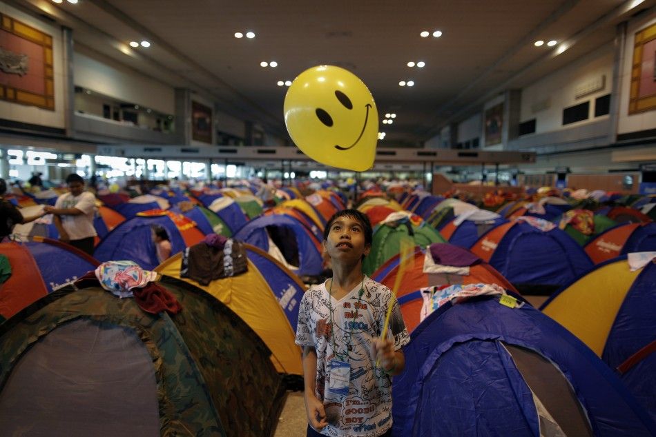 A boy, evacuated from area affected by floods, plays with a balloon at the collective shelter at the Don Mueang airport in Bangkok