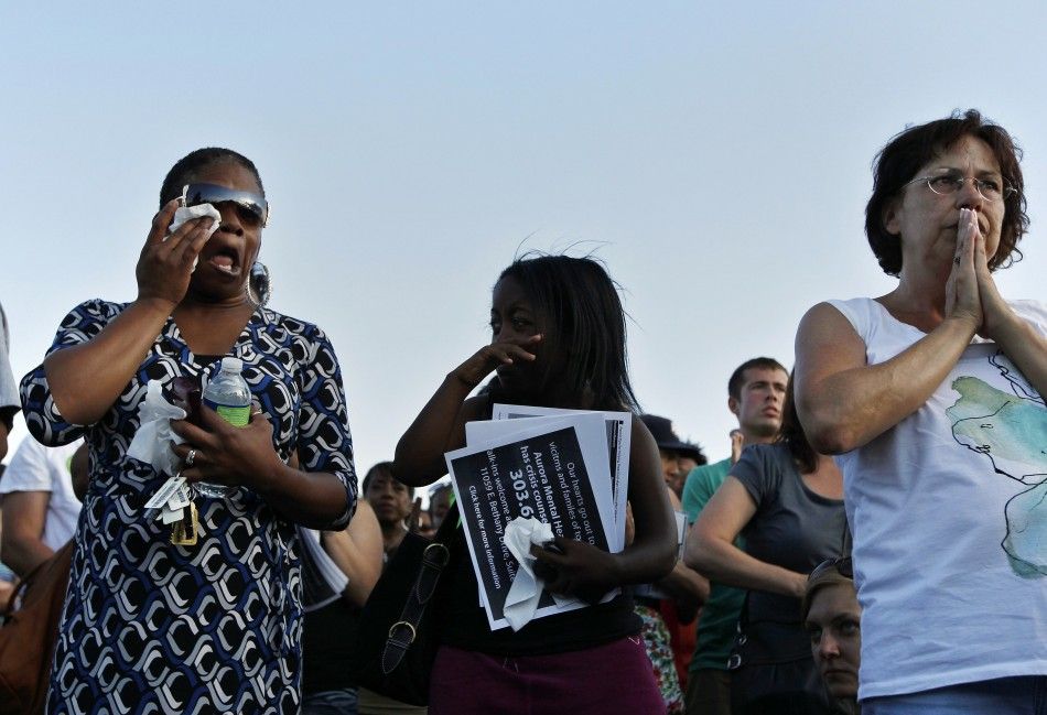 People pray during a vigil for victims behind the theater where a gunman opened fire in Aurora, Colorado