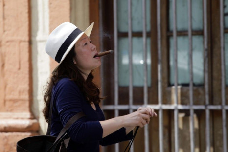 A woman smoking a cigar arrives at the Partagas factory in Havana for a visit during the ongoing annual Cuban cigar festival