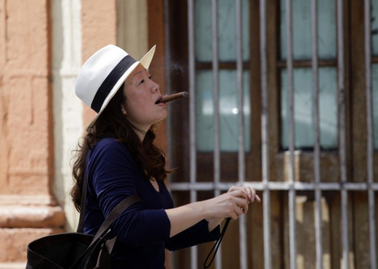 A woman smoking a cigar arrives at the Partagas factory in Havana for a visit during the ongoing annual Cuban cigar festival