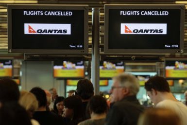 Stranded Qantas passengers line up as they seek information at the check in counters after their flights were cancelled at Singapore Changi Airport