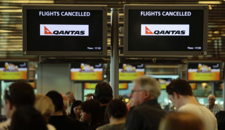 Stranded Qantas passengers line up as they seek information at the check in counters after their flights were cancelled at Singapore Changi Airport