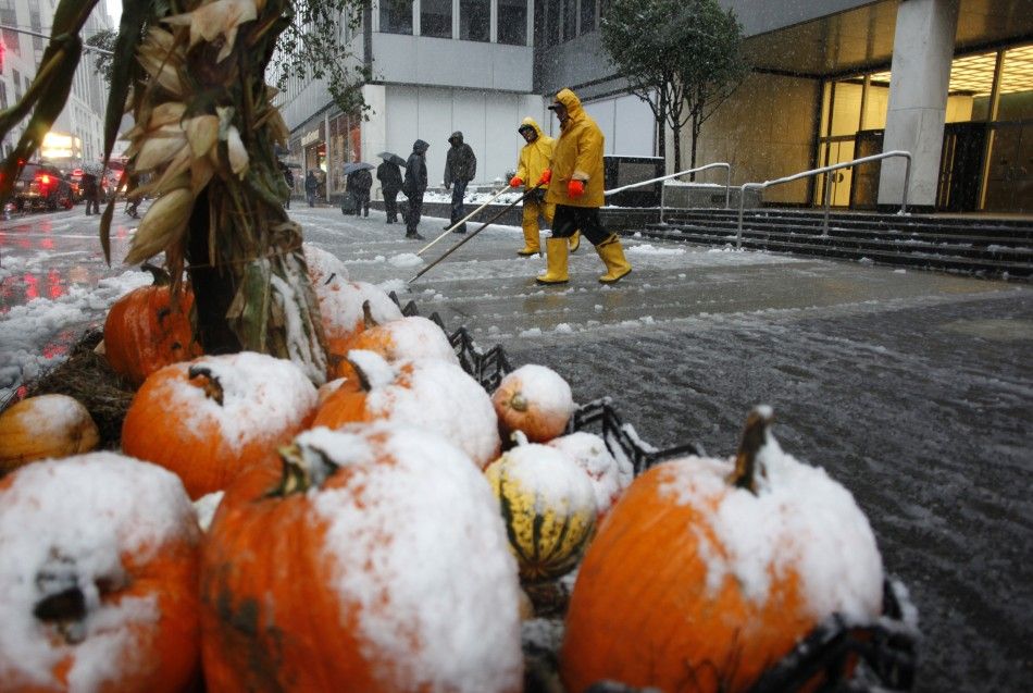 Workers clear snow from the sidewalks as a decorative display of pumpkins are coated in snow in New York, October 29, 2011. A rare October snowstorm bore down on the heavily populated U.S. Northeast on Saturday, with some areas bracing for up to a foot 3