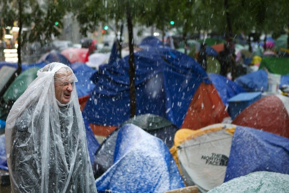 A member of the Occupy Wall Street movement surveys tents set up in Zuccotti Park during the first winter snow fall in New York October 29, 2011.