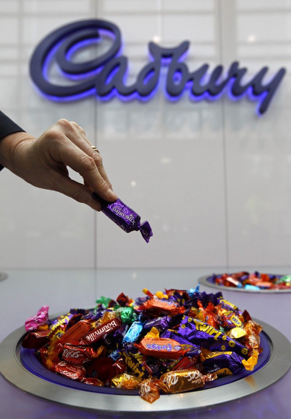 A woman takes a chocolate from a bowl at the Cadbury factory