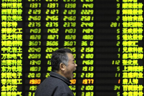 An investor yaws as he walks past an electrical board showing stock information at a brokerage house in Nanjing