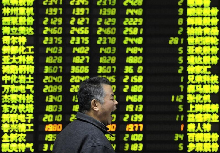 An investor yaws as he walks past an electrical board showing stock information at a brokerage house in Nanjing