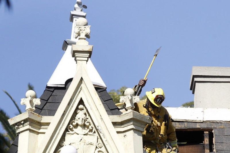 A firefighter is seen on the roof of the Magic Castle after an attic fire broke out in Hollywood