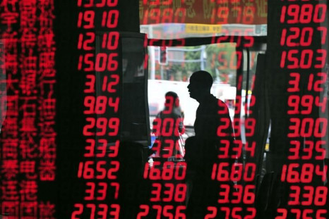 An investor is reflected in a screen showing stock information at a brokerage house in Shenyang