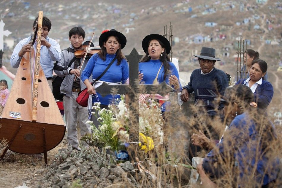 Andean singers perform in front of a grave during the Day of the Dead celebrations in Nueva Esperanza cemetery in Villa Maria, Lima November 1, 2011. Each year people visit the cemetery, one of Latin America039s largest, to honour the dead