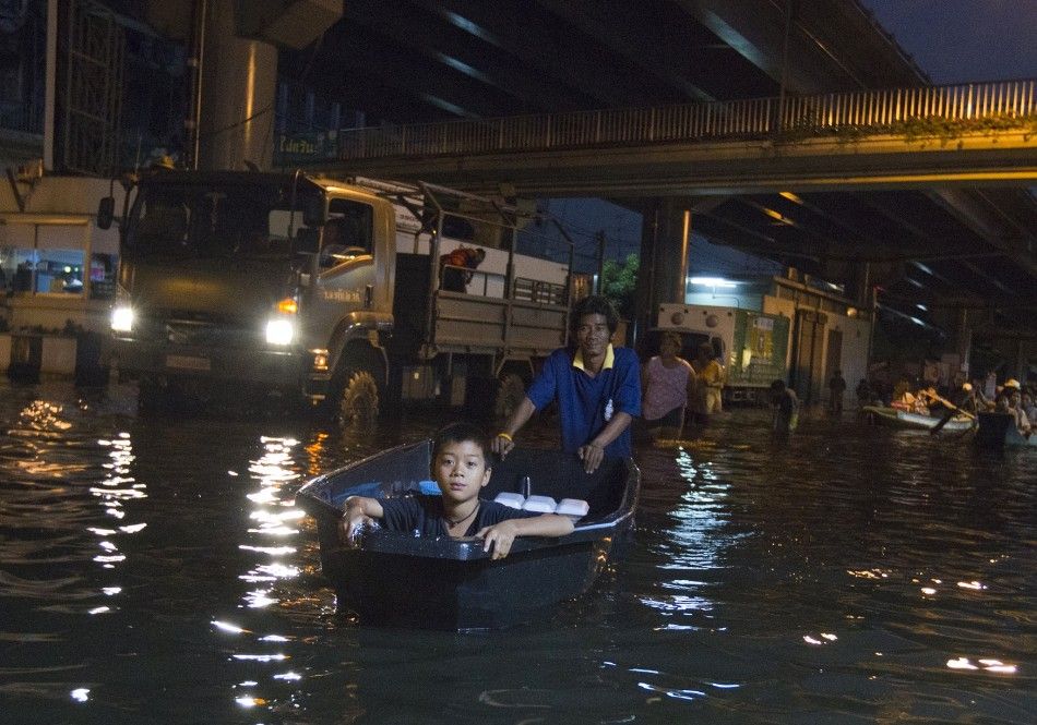 A man uses a boat to transport a boy through the flooded streets of Bang Phlat district in Bangkok on November 1, 2011.