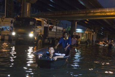 A man uses a boat to transport a boy through the flooded streets of Bang Phlat district in Bangkok on November 1, 2011.