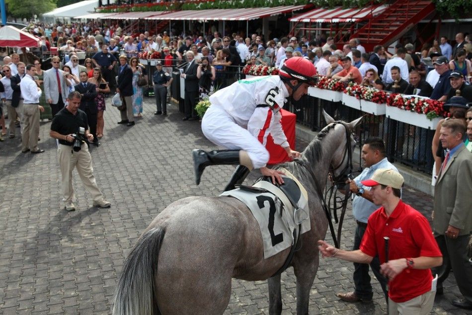 A jockey dismounts in the winners circle at the Saratoga Race Course opening weekend.