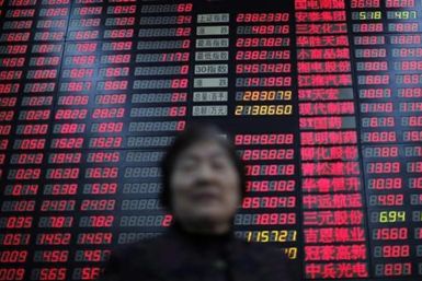An investor stands in front of an electrical board showing stock information at a brokerage house in Shanghai
