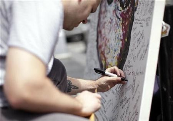 A man writes a message on artist Geoffrey Raymond&#039;s painting of News Corp CEO Rupert Murdoch, titled &#039;&#039;Inverted Murdoch&#039;&#039;, in front of the NewsCorp building in New York