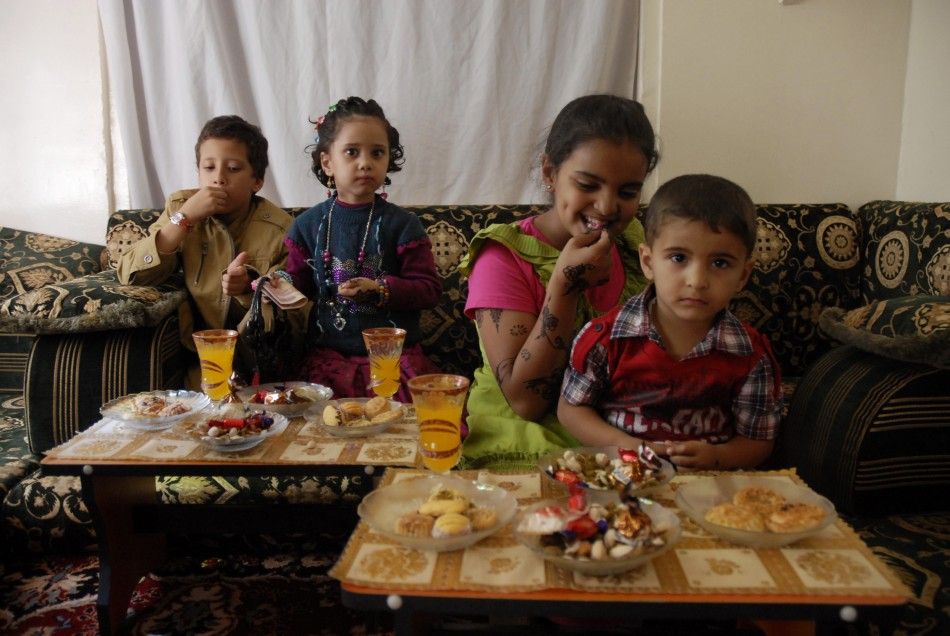 Children wearing new clothes eat candy and cakes on the first day of Eid al-Adha in in Sanaa November 6, 2011.