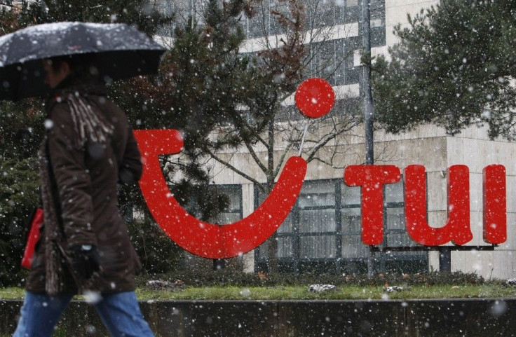 Woman with an umbrella walk past the logo of German travel company TUI AG outside the company&#039;s headquarters during snowfall in Hanover