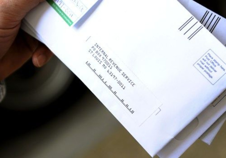 A man holds his envelopes as he waits in line to mail his family's income tax returns at a mobile post office near the Internal Revenue Service building in downtown Washington