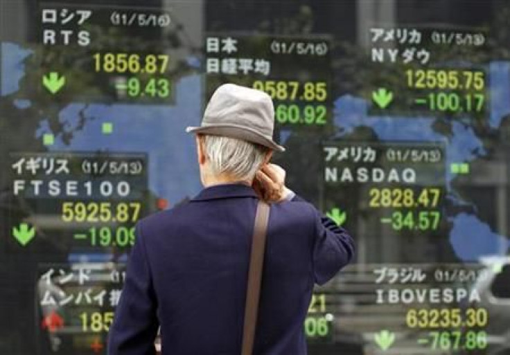 Man looks at an electronic board displaying various market indices from around the world outside a brokerage in Tokyo