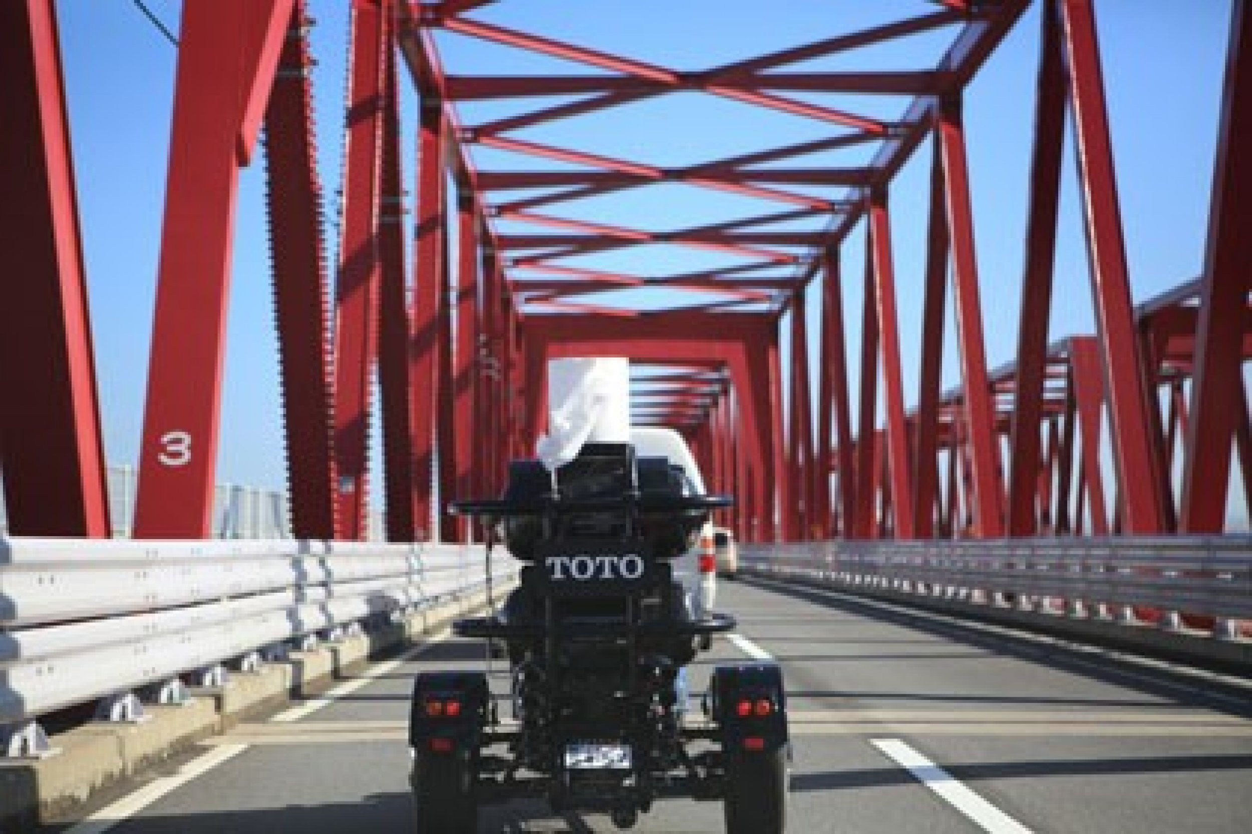 The Toilet Bike Neo crosses a bridge.