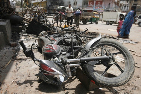 Commuters walk past debris of burnt vehicles after a clash between two communities at Sanand