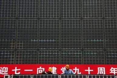 Workers stand atop scaffolding as they work on a building covered in solar panels located near the factory of the Yingli Green Energy Holding Company, also known as Yingli Solar, located in the city of Baoding, Hebei Province June 20, 2011.