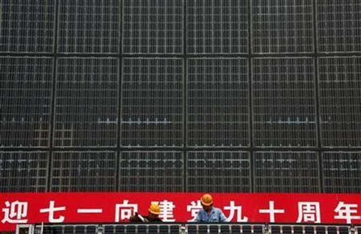 Workers stand atop scaffolding as they work on a building covered in solar panels located near the factory of the Yingli Green Energy Holding Company, also known as Yingli Solar, located in the city of Baoding, Hebei Province June 20, 2011.