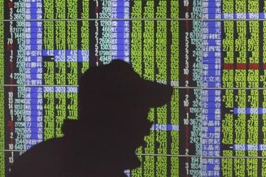 A man's shadow is cast on monitors displaying stock market prices inside a brokerage in Taipei