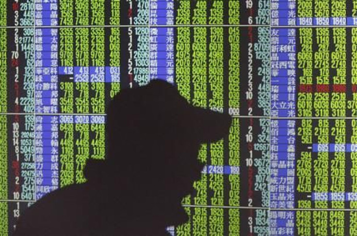 A man's shadow is cast on monitors displaying stock market prices inside a brokerage in Taipei