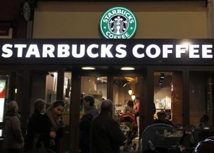 Customers are seen at a Starbucks coffee store which displays their old logo in Paris