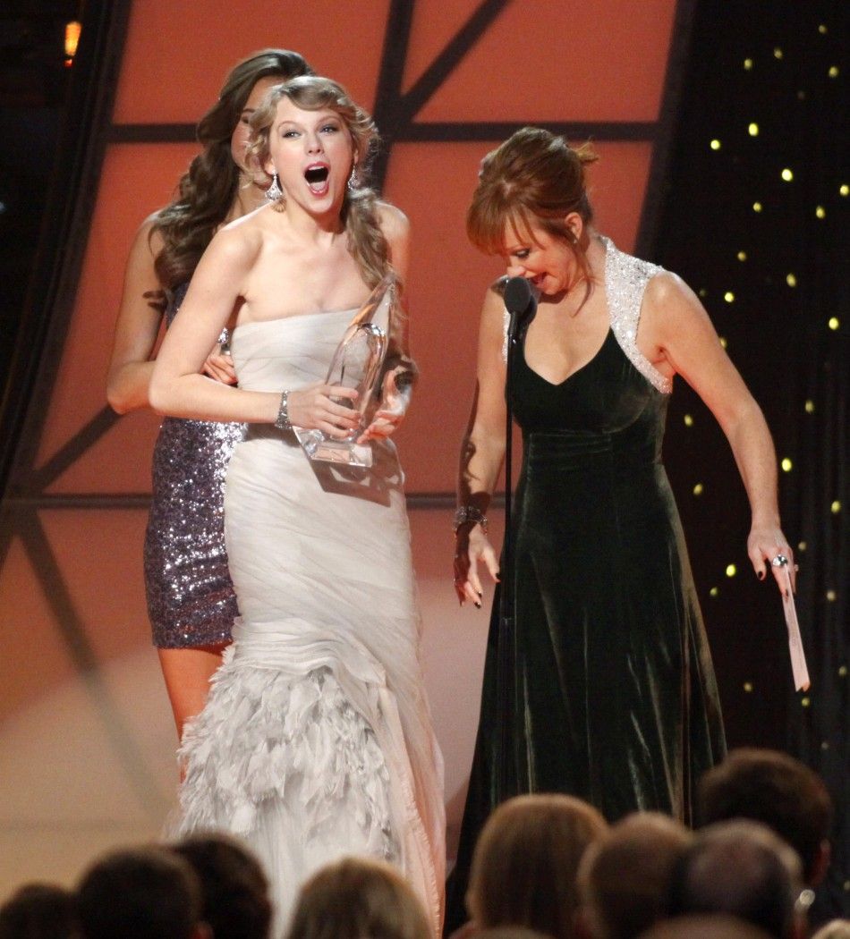 Singer Taylor Swift accepts award for Entertainer of the Year from presenter Reba McEntire at the 45th Country Music Association Awards in Nashville