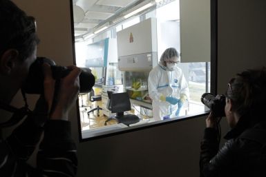 Photographers take a picture of a lab assistant preparing an experiment at new P3 level research laboratory against tuberculosis in Lausanne.
